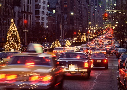 A busy road full of cars is pictured at night time with Christmas lights in the background